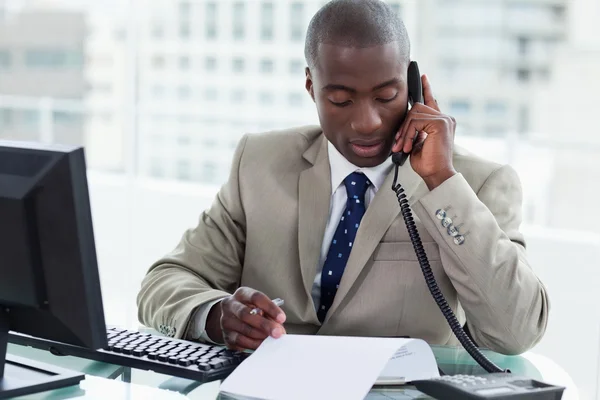 Entrepreneur making a phone call while reading a document — Stock Photo, Image