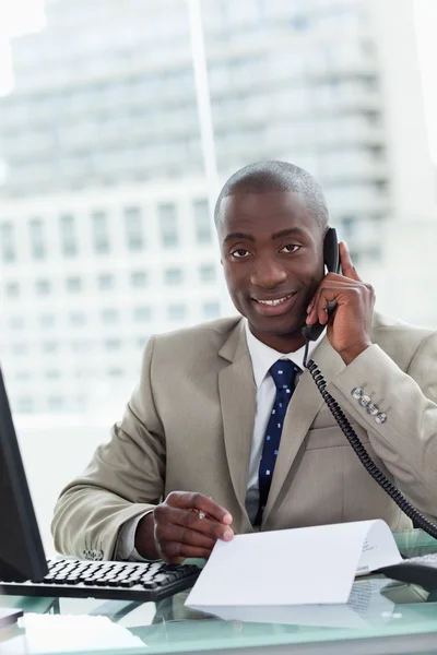 Portrait of a smiling entrepreneur making a phone call while rea — Stock Photo, Image