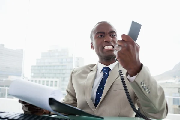 Homem de negócios irritado olhando para seu telefone auscultador — Fotografia de Stock