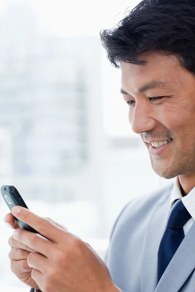 Portret van een glimlachende kantoor werknemer gebruik van zijn mobiele telefoon — Stockfoto