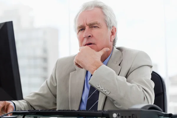 Thoughtful senior manager working with a monitor — Stock Photo, Image