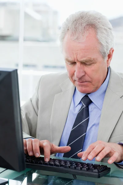 Retrato de un gerente senior serio usando una computadora en su oficina —  Fotos de Stock
