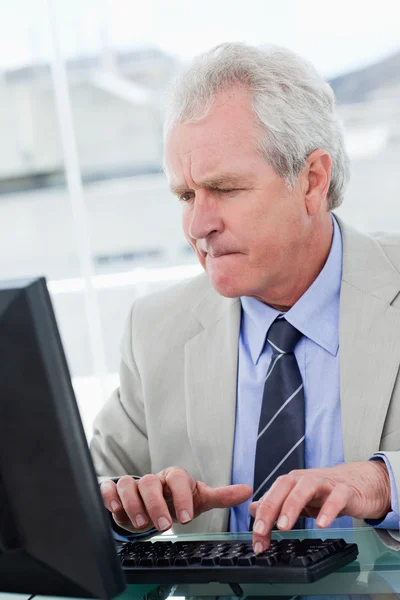 Porträtt av en allvarlig senior manager som använder en dator — Stockfoto