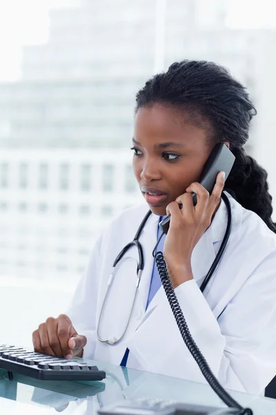 Portrait of a female doctor using a computer while being on the — Stock Photo, Image