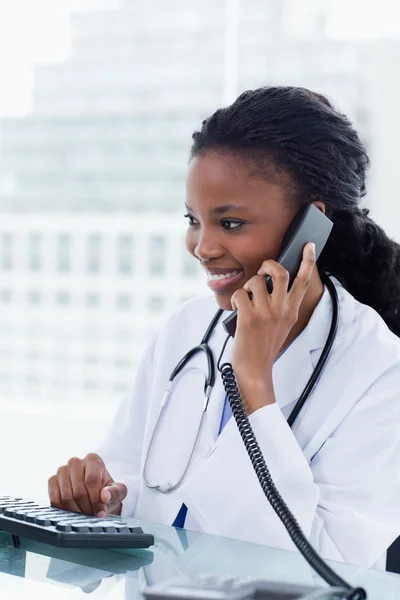 コンピューターの使用中の携帯電話上の女性医師の肖像画 — ストック写真