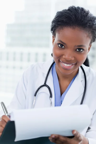 Retrato de uma médica sorridente assinando um documento — Fotografia de Stock