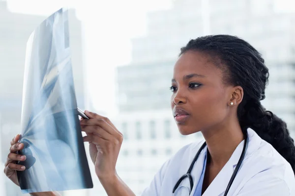 Médico femenino enfocado mirando un conjunto de rayos X — Foto de Stock