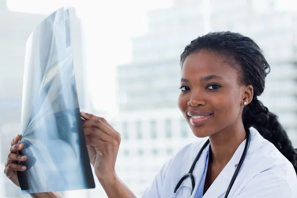 Улыбающаяся женщина-врач смотрит на рентген — стоковое фото