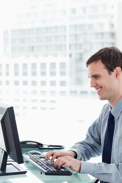 Πλάγια όψη της ένα χαμογελαστό εργαζόμενος γραφείου χρησιμοποιώντας μια οθόνη — Φωτογραφία Αρχείου