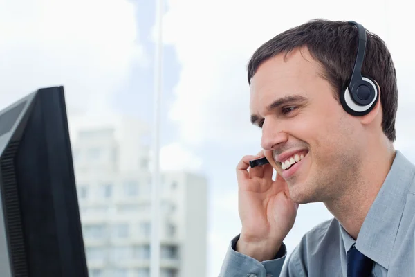 Gülümseyen bir kulaklık kullanarak ofis çalışanı — Stok fotoğraf
