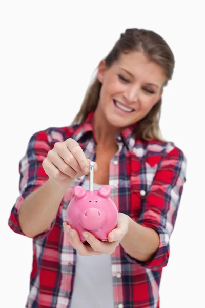 Retrato de uma jovem mulher colocando uma nota um banco porquinho — Fotografia de Stock