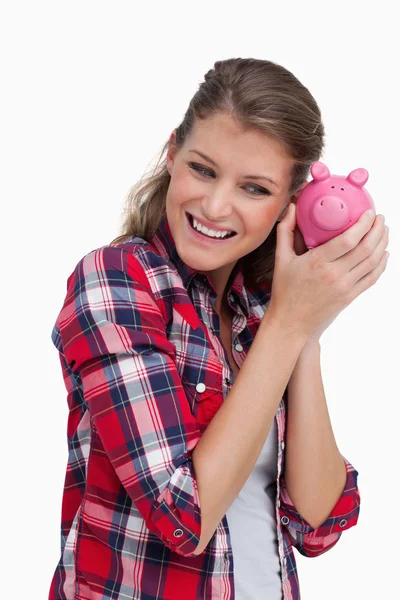 Portrait of a young woman shaking a piggy bank — Stock Photo, Image