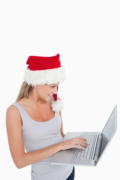 使用一台笔记本电脑的圣诞帽子的女人 — 图库照片