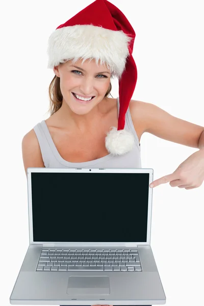 Kobieta w kapeluszu Boże Narodzenie, wskazując na notebooka — Zdjęcie stockowe