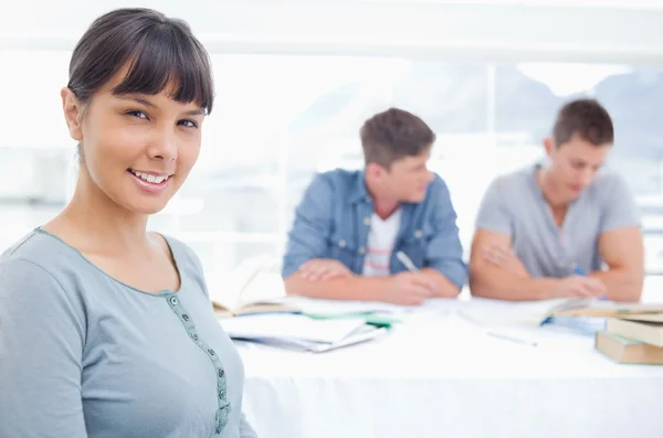 A woman sits in front of to men as she looks at the camera — Stock Photo, Image