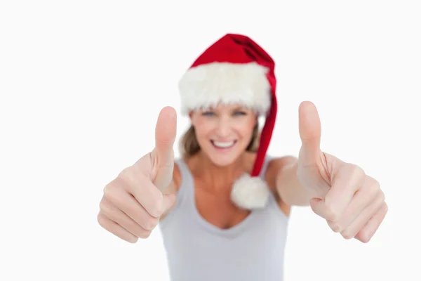 親指で女性まで笑ってとクリスマスの帽子 ストック写真