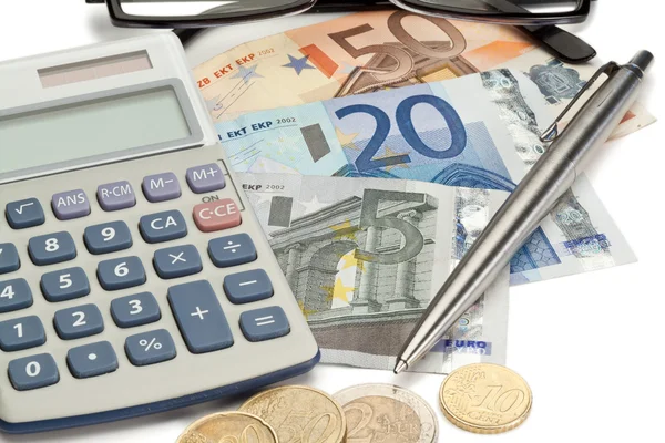 Moedas e dinheiro com caneta junto com óculos e calculadora de bolso — Fotografia de Stock