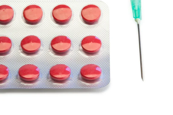 Blister strip of red pills and syringe — Stock Photo, Image