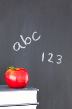 Stack of books with a red apple and a blackboard with figures an clipart