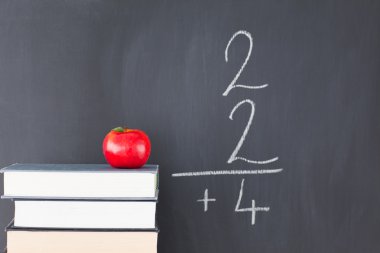 Stack of books with a red apple and a blackboard with a simple f clipart