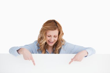 Smiling blond-haired woman standing behind an empty white board clipart