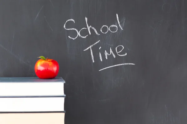 Stack of books with a red apple and a blackboard with "school ti — Stock Photo, Image