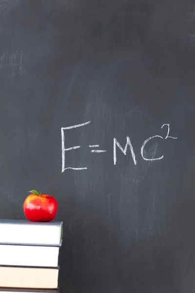 Stapel boeken met een rode apple en een schoolbord met een formule — Stockfoto