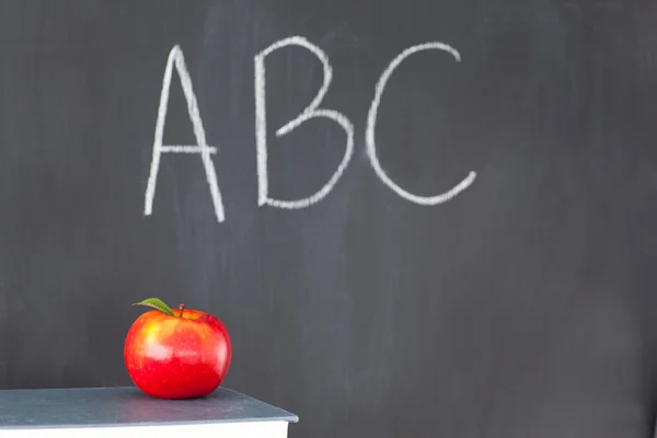 Stack of books with a red apple and a blackboard with "ABC" writ — Stock Photo, Image