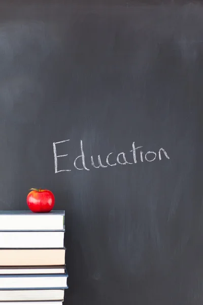 Stack of books with a red apple and a blackboard with "education — Stock Photo, Image