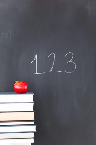 Montón de libros con una manzana roja y una pizarra con "123" escrito — Foto de Stock