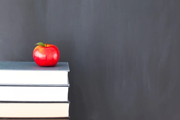 Kırmızı elma ve temiz bir kara tahta kitap yığını — Stok fotoğraf