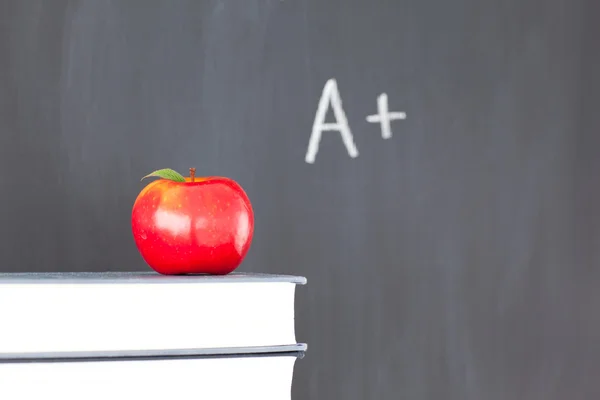 Kırmızı elma ile kitap ve yazı tahtası "artı" yığını üzerinde yazılı — Stok fotoğraf
