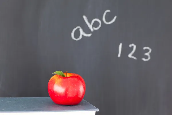 Bunt böcker med ett rött äpple och en svart tavla med siffror en — Stockfoto