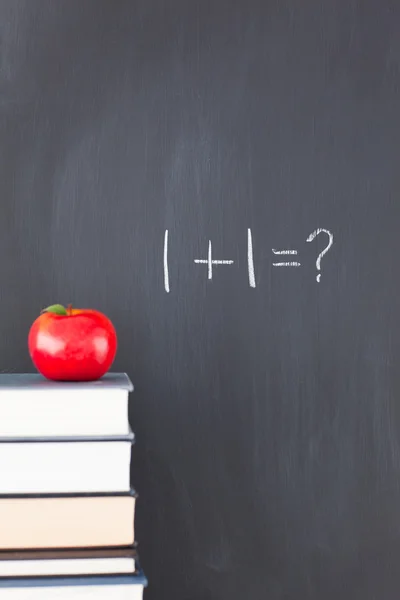 Stack of books with a red apple and a blackboard with exercise written on it — Stock Photo, Image