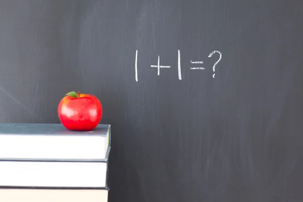 Bücherstapel mit einem roten Apfel und einer Tafel mit Übungen darauf — Stockfoto