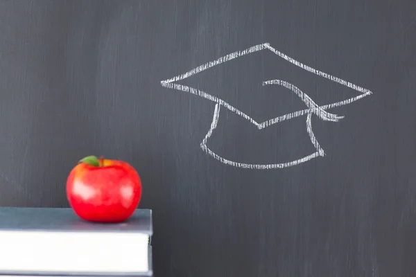 Stapel boeken met een rode apple en een schoolbord met een graduati — Stockfoto