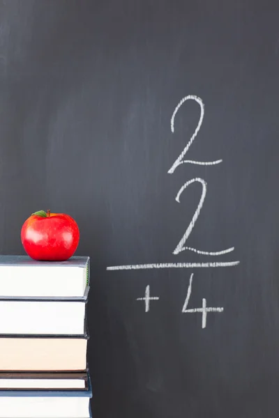 Stapel boeken met een rode apple en een schoolbord met een eenvoudige f — Stockfoto