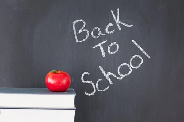 Stack of books with a red apple and a blackboard with "back to s — Stock Photo, Image