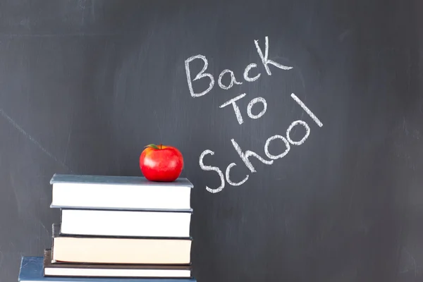 Stack of books with a red apple and a blackboard with "back to s — Stock Photo, Image