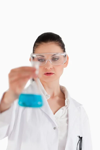 Científica que lleva gafas de seguridad y sostiene un frasco azul —  Fotos de Stock