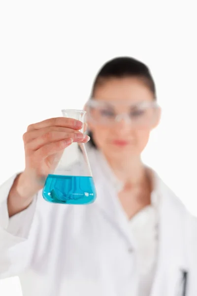 Kvinnlig vetenskapsman med skyddsglasögon innehar en blå kolv — Stockfoto
