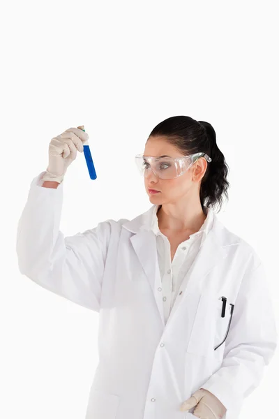 Cientista de cabelos escuros a olhar para um tubo de ensaio — Fotografia de Stock