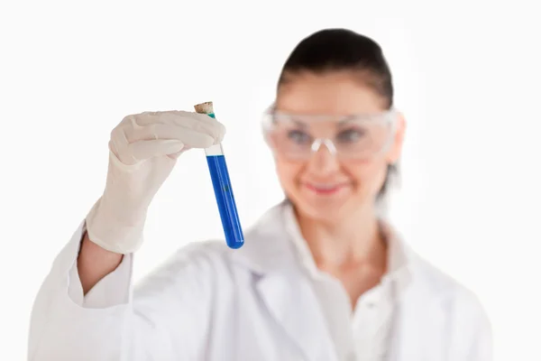 Wissenschaftlerin blickt auf blaues Reagenzglas — Stockfoto