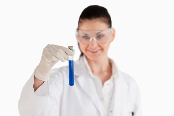 Χαμογελώντας θηλυκός επιστήμονας κοιτάζοντας ένα μπλε δοκιμαστικό σωλήνα — Φωτογραφία Αρχείου