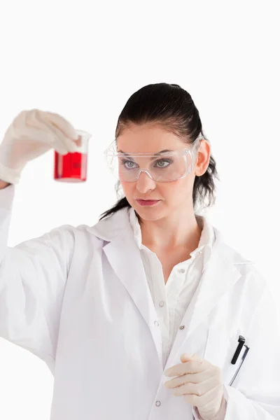 Cientista de cabelos escuros conduzindo uma experiência olhando para um vermelho — Fotografia de Stock