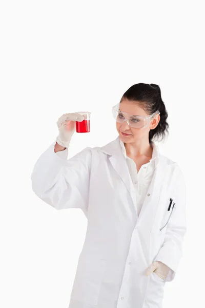 Mulher cientista olhando para um copo vermelho — Fotografia de Stock