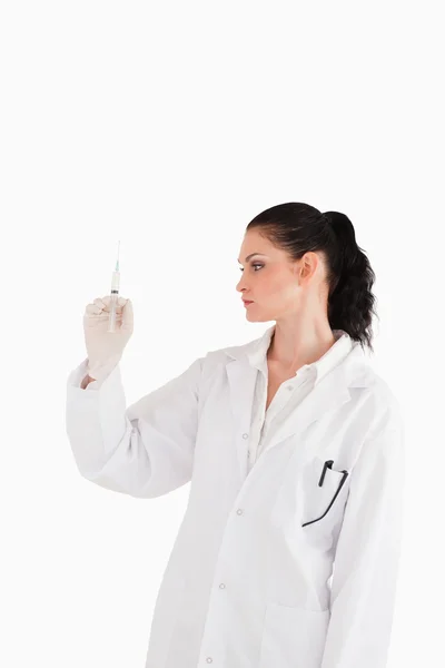 Mörkhårig läkare titta på en spruta — Stockfoto