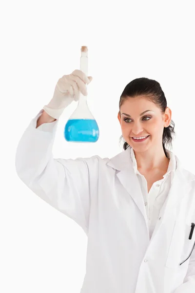Cientista sorridente de cabelos escuros olhando para um frasco — Fotografia de Stock