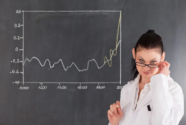 Dark-haired scientist standing near the blackboard — Stock Photo, Image