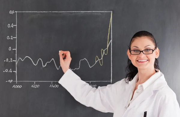 Smiling scientist drawing charts on the blackboard — Stock Photo, Image